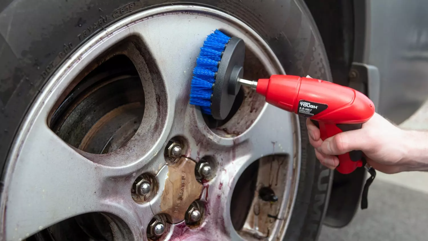 The Tirekit Brush being used to clean the wheel of a vehicle.