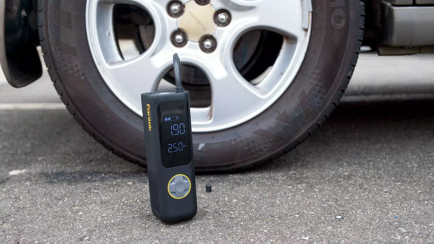 The Fanttik inflator being used on a testing vehicle tire.