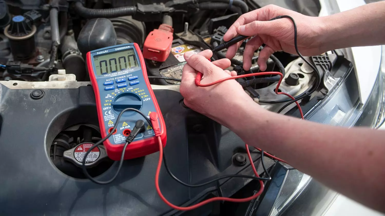 The AstroAI TRMS 6000 Digital Multimeter being used to measure voltage, current, and other electric components in a vehicle.